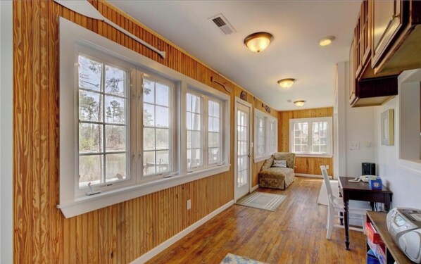 A room with wooden paneling, large windows, a sofa, a desk, and a chair.