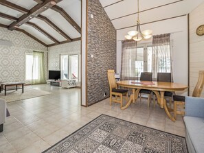 A spacious living area with a dining table, chairs, a television, and a stone accent wall. - Lake suite by Interhome (Hollola)