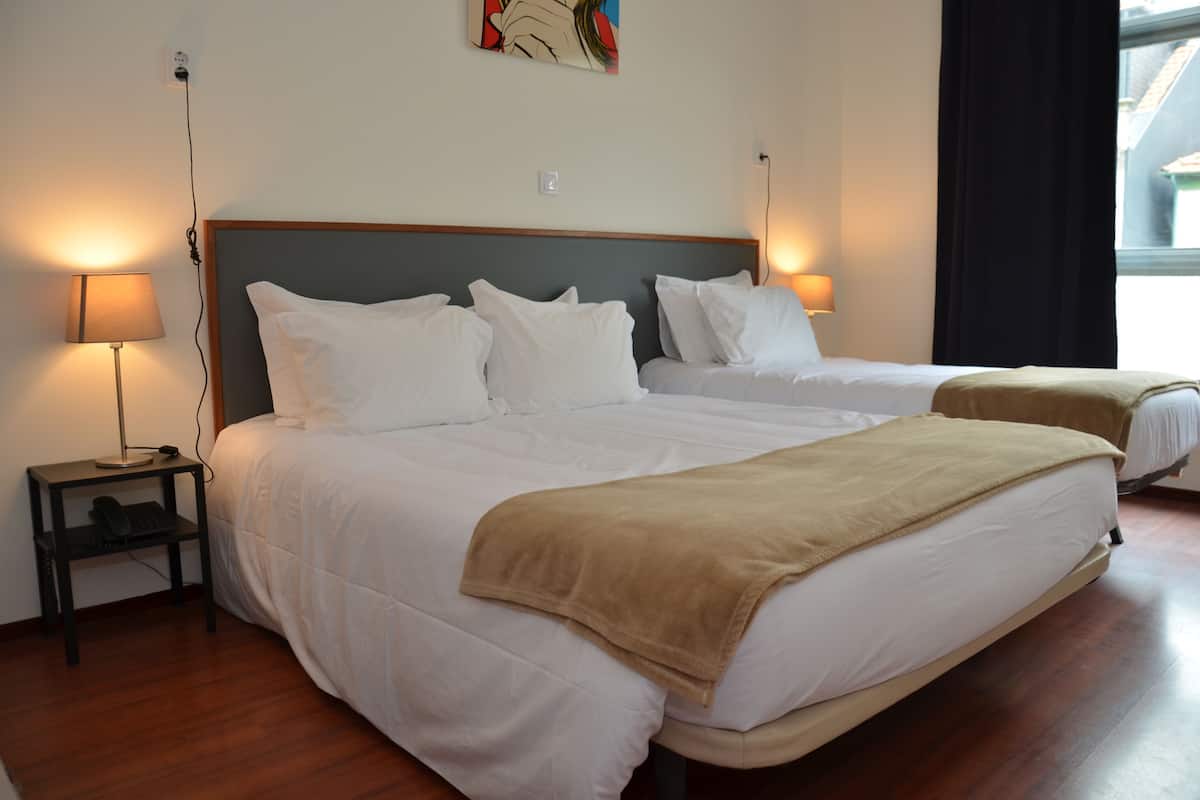 A hotel room with two beds, a nightstand with a lamp, and a painting on the wall.
