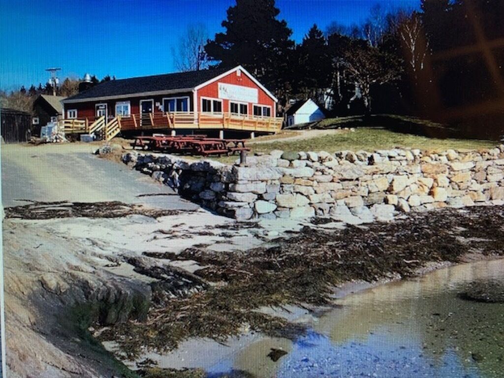 A red building with a stone wall in front, a wooden deck, and a clear sky.