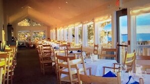 A restaurant with long tables and chairs, large windows, and a view of the outdoors. - New Listing - Island View Cottage (Phippsburg)