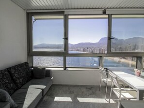 A modern room with a large window, a sofa, a dining table, and chairs.