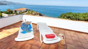 A terrace with two white sun loungers, a beach view, and a small house in the background. - Don Quijote by Interhome (Llançà)