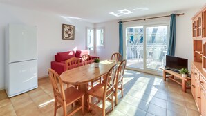 Un espace de vie compact comprenant un coin repas, un canapé, un téléviseur et un balcon avec vue.