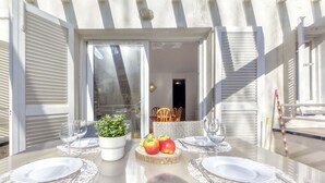 Un espace de restauration en plein air avec une table en verre, des assiettes blanches et une plante en pot.