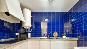 Une cuisine avec des carreaux bleus, un four à micro-ondes, un évier et un lave-vaisselle.