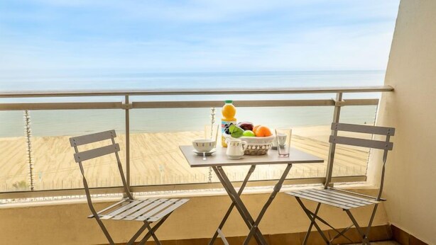 A balcony with a table set for breakfast, overlooking a beach. - Apartment Milos by Interhome (Canet-Plage)