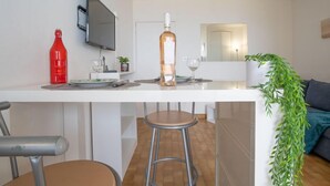 A modern kitchen with a white countertop, a red bottle, a TV, and a plant. - Apartment Milos by Interhome (Canet-Plage)