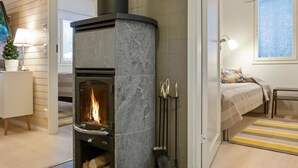 Una sala moderna con chimenea de piedra, una cama y una pequeña mesa.