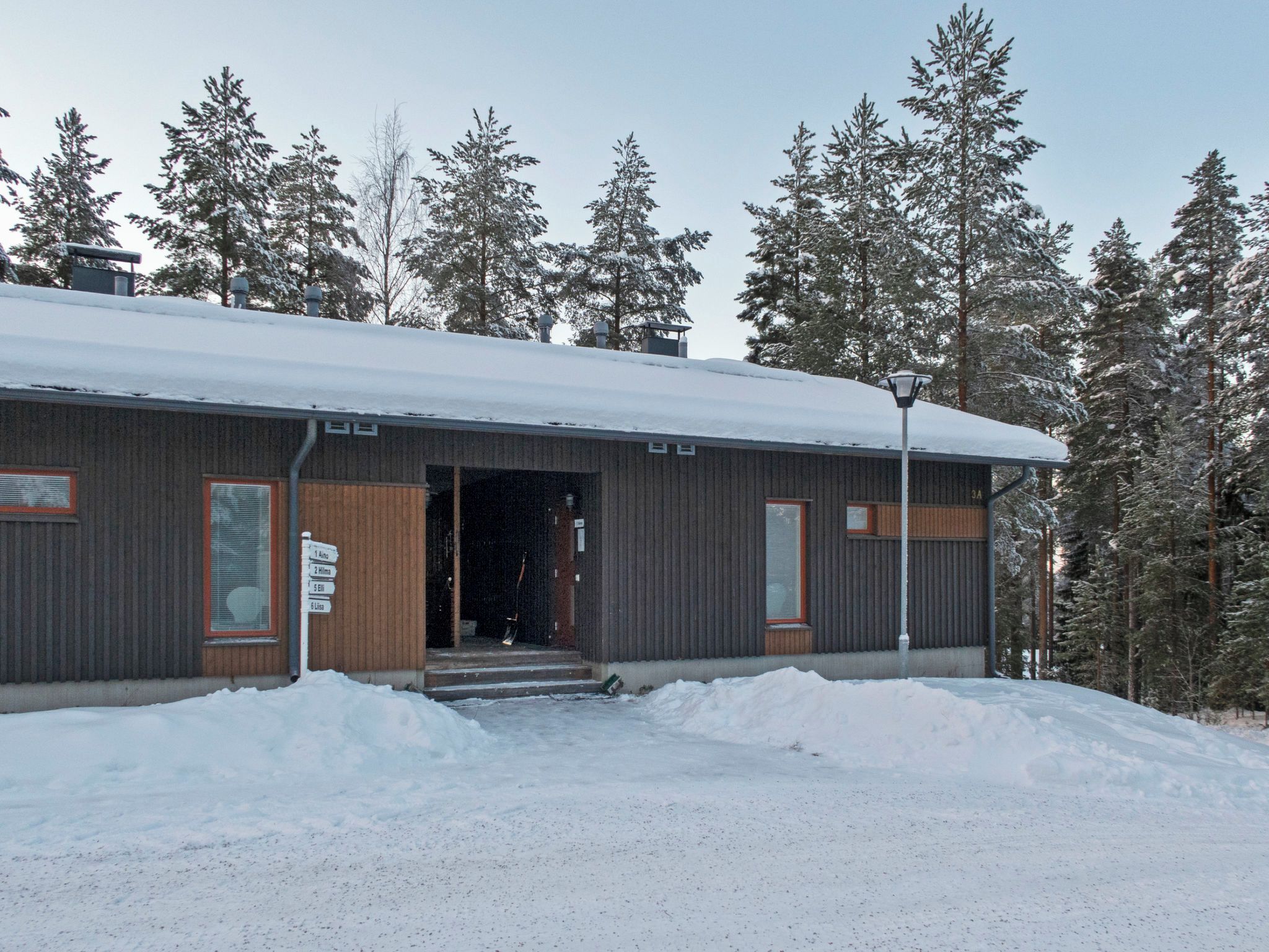 Un edificio moderno con facciata in metallo, una porta in legno e una segnaletica direzionale.