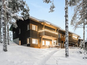 A modern multi-story building with a snow-covered landscape, large windows, and a balcony. - Vacation home Aino by Interhome (Sotkamo)