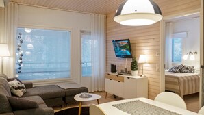 Una sala de estar moderna con un sofá, una mesa de comedor y un televisor montado en la pared.