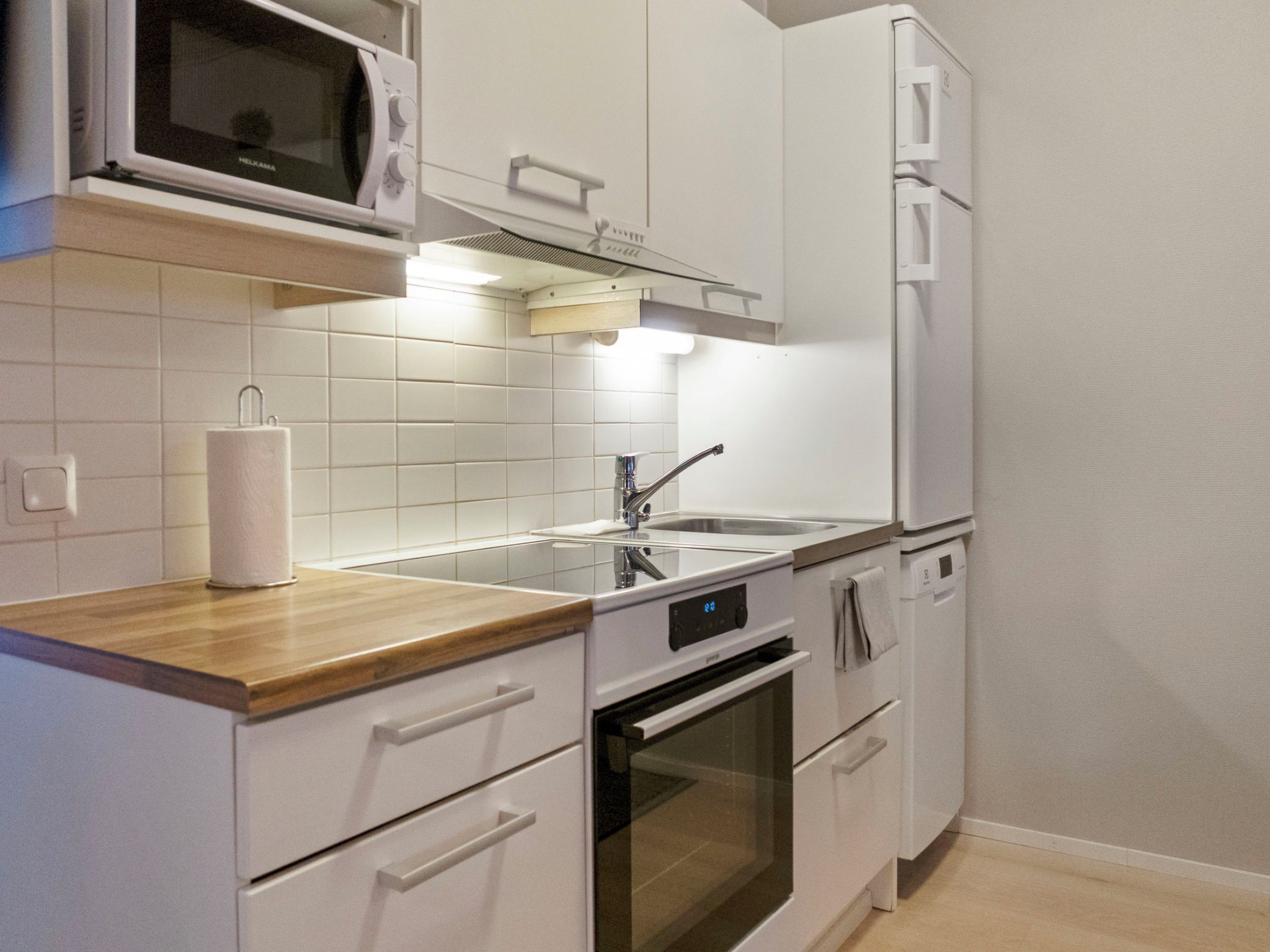 A modern kitchen with white cabinetry, a stainless steel sink, and a microwave above the counter.