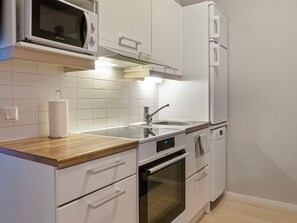 A modern kitchen with white cabinetry, a stainless steel sink, and a microwave above the counter.
