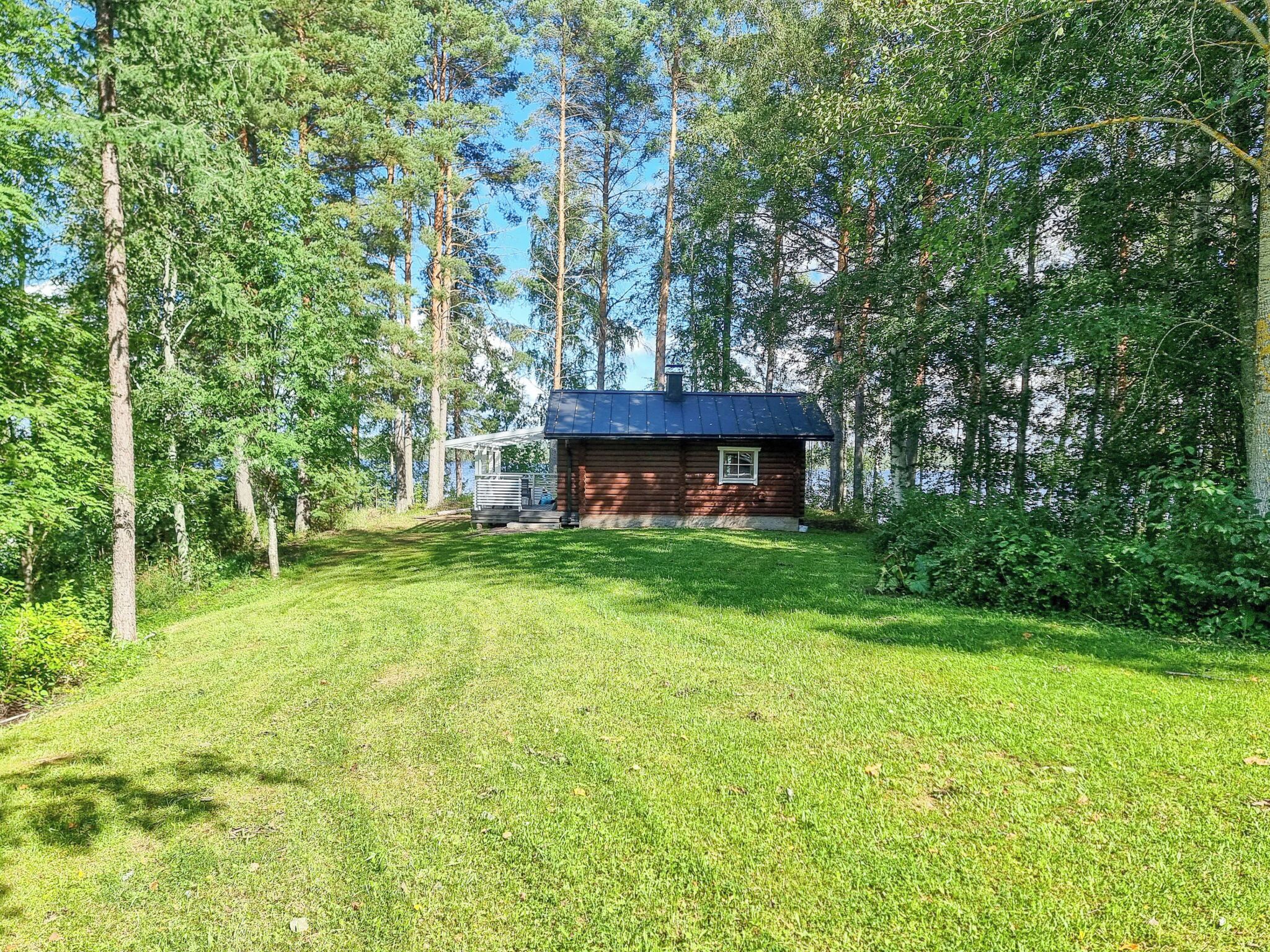 Mökki, jonka ympärillä on nurmialuetta ja korkeita puita.