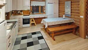 Una cocina compacta con armarios blancos, un banco de madera y una alfombra a cuadros.