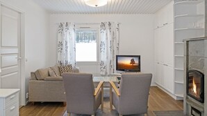 Ett modernt vardagsrum med en soffa, två fåtöljer, en tv och en öppen spis.