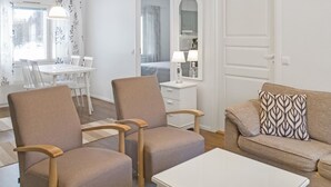 Ett modernt vardagsrum med två fåtöljer, en soffa, ett soffbord och en matplats med ett bord och stolar.