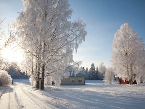 A snow-covered landscape with a house and trees.