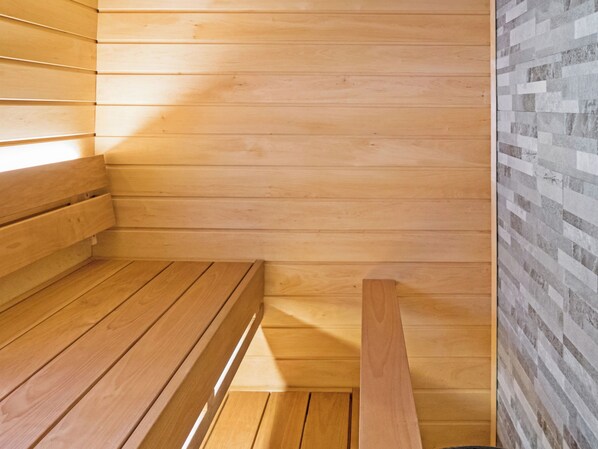 A sauna room with wooden benches and a tiled wall.
