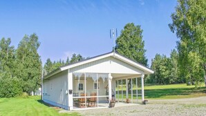 En enplansbyggnad med en täckt uteplats, en liten sittplats utomhus och en grusuppfart.