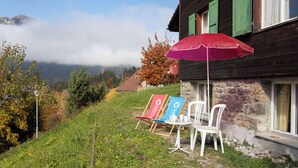 A wooden house with stone walls, a red umbrella, and outdoor seating. - Helene Studio Christel by Interhome (Wengen)
