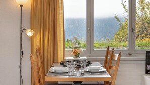 A dining table set for four with a view of mountains through a window. - Helene Studio Christel by Interhome (Wengen)