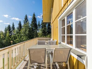 Eine Holzterrasse mit Tisch und Stühlen, mit Blick auf eine bewaldete Landschaft.