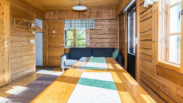Ein Holzblockhaus-Interieur mit einer Couch, einem Tisch und einer Pendelleuchte.