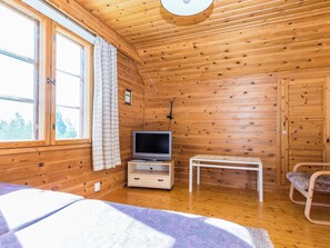 Ein Zimmer in einer Holzhütte mit einem Fernseher auf einem Holzständer, einem kleinen Tisch und einem Stuhl.