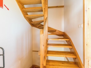A wooden spiral staircase with a metal handrail, leading to an upper floor.