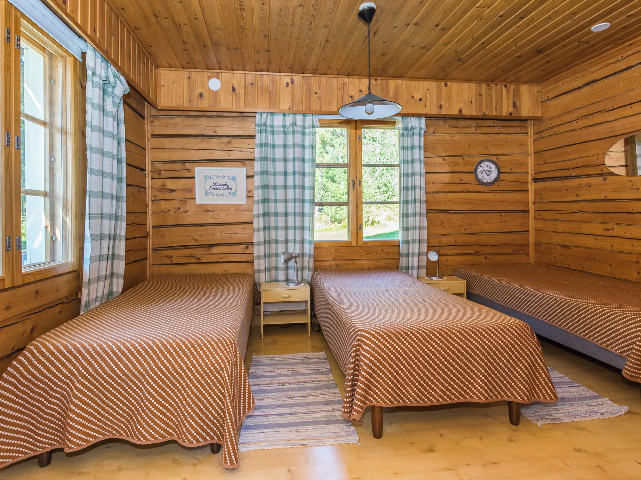 A cabin with two single beds, a small table, a lamp, and a window with curtains.