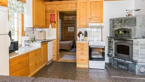 Eine kleine Küche mit Holzausstattung, einem eingebauten Backofen und einem Kamin aus Stein.