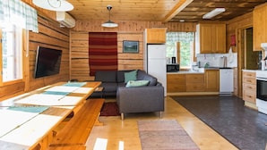 Ein gemütliches Blockhaus-Interieur mit Essbereich, Sofa, Küche und Holzwänden.