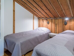 Une chambre avec deux lits simples, des murs en bois et un plafond en pente.