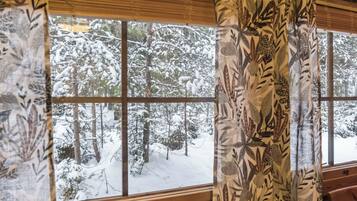 A window with a view of a snowy forest.