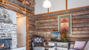 Een gezellige woonkamer met een stenen openhaard, een wand van houten boomstammen en moderne meubels.