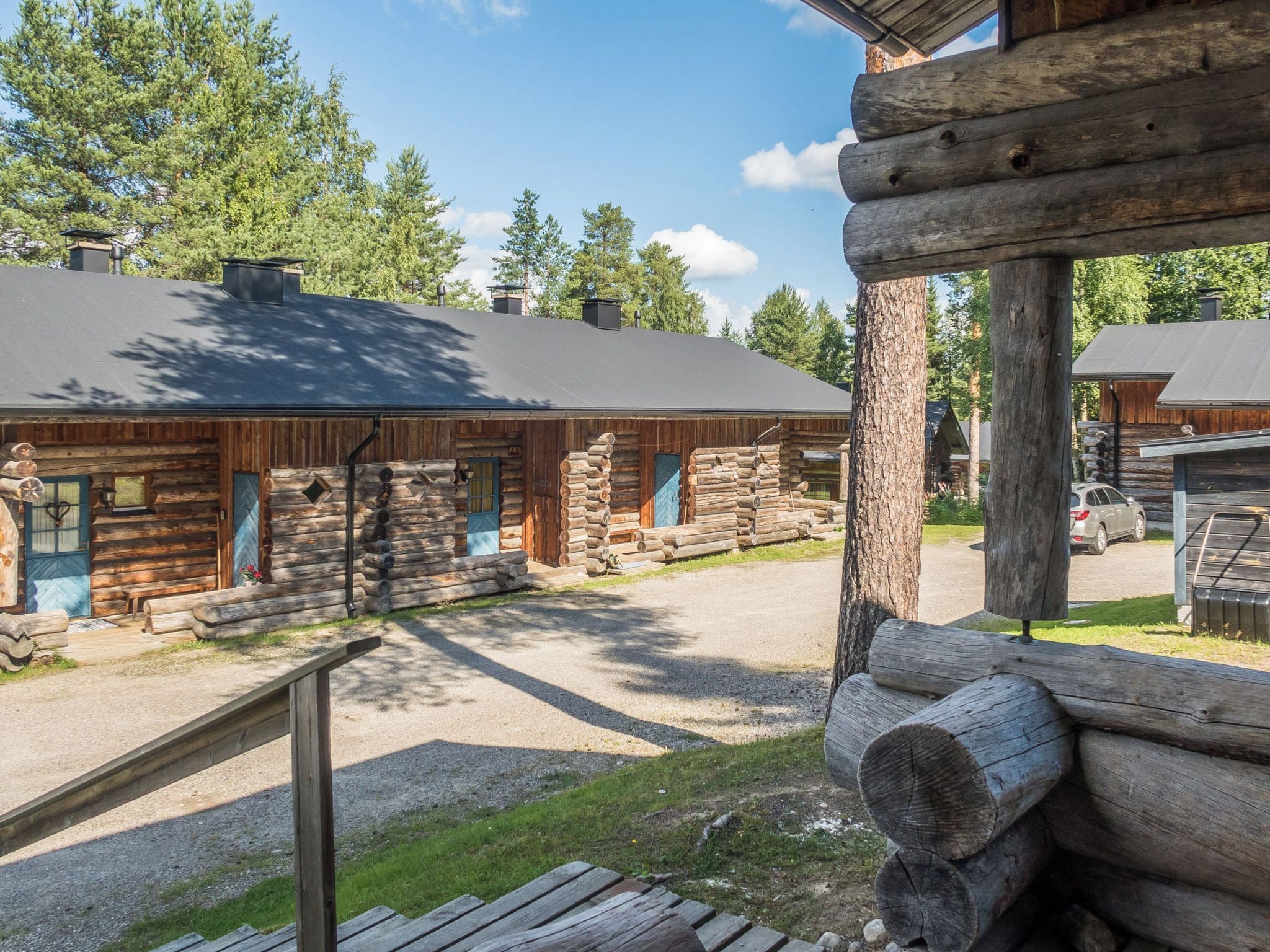 A log cabin with a gravel driveway and a wooden deck.