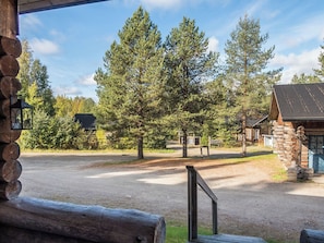 Un chalet rustique avec une allée en gravier, entouré de grands pins.