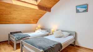 A cozy attic bedroom with two single beds, wooden ceiling beams, and a skylight. - Vacation home Sicard by Interhome (Mimizan)