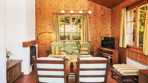 Una cabaña de madera acogedora con comedor, sofá y televisor.