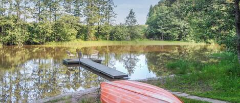 A calm lake with a dock and a red boat.