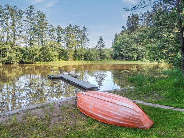 A calm lake with a dock and a red boat.