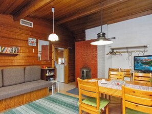 Ein gemütliches Wohnzimmer mit einer Couch, einem Esstisch mit Stühlen, einem Fernseher und einem Bücherregal.