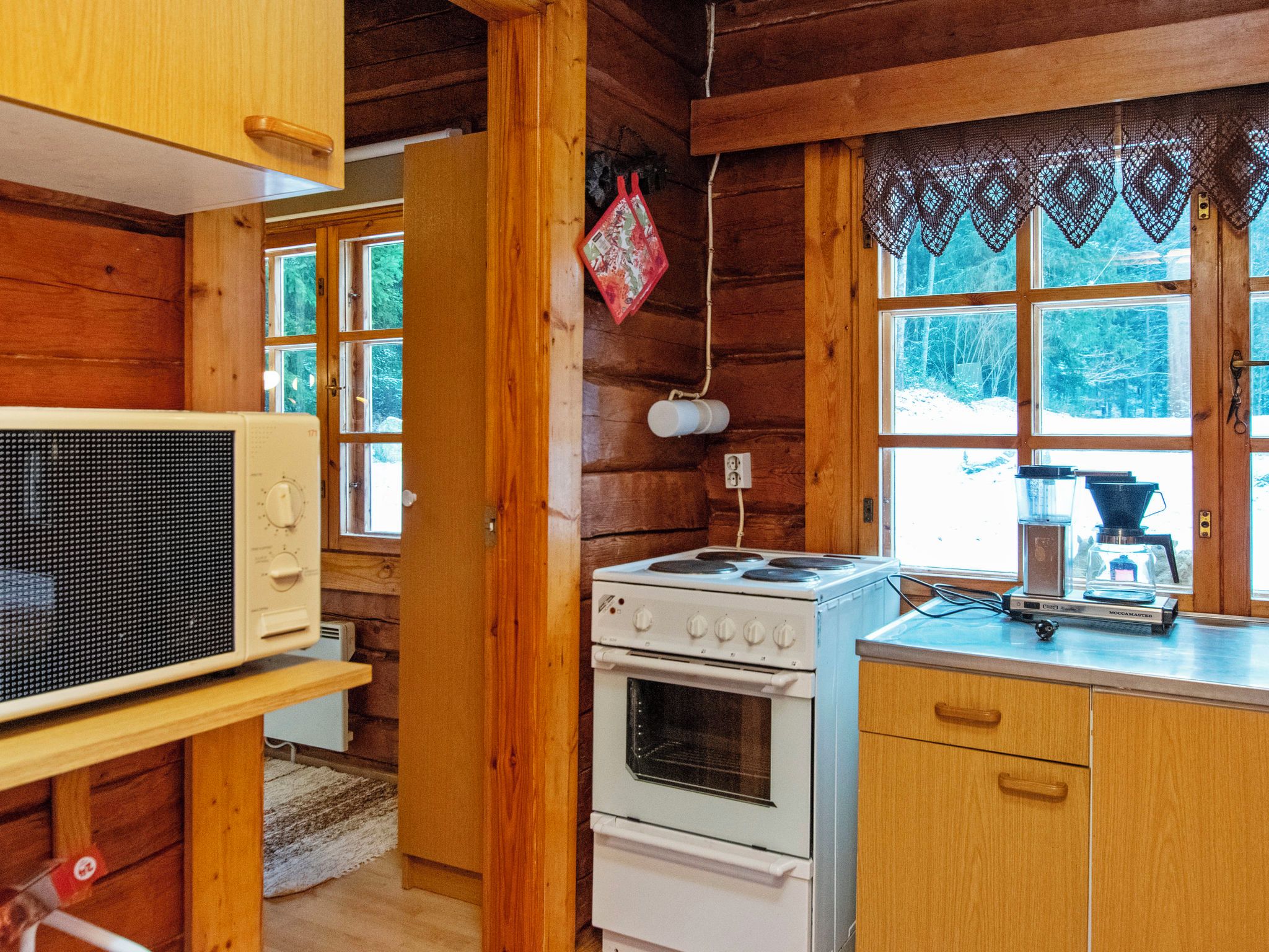 Une cuisine de style rustique, équipée d’une cuisinière, d’un four, d’un four à micro-ondes et de meubles de rangement en bois.