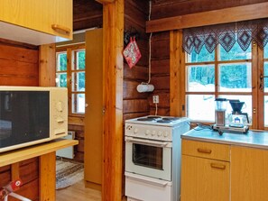 Eine Küchenzeile in einer Hütte mit Herd, Backofen, Mikrowelle und Holzschränken.
