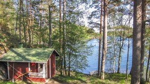 A cabin with a green roof, situated by a lake surrounded by tall trees. - Suvituuli by Interhome (Punkaharju)