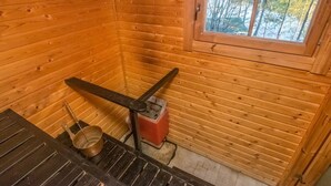 A wooden cabin interior with a window, a metal stove, and a metal bucket. - Suvituuli by Interhome (Punkaharju)