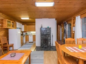 Cozy cabin-style room with a kitchen area, black fireplace, and dining space.