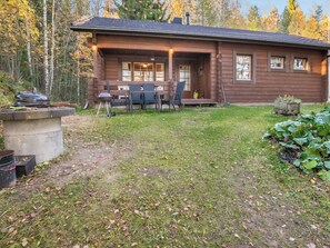 A wooden cabin with a patio area, outdoor seating, and a grill.